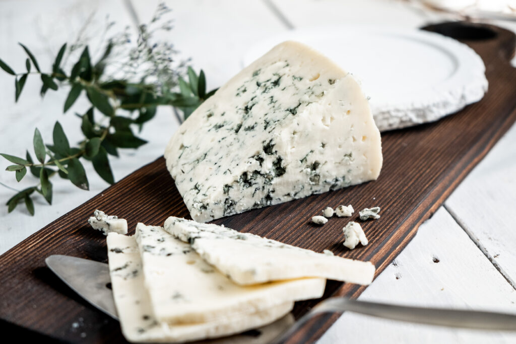 A piece of dor blue cheese on a cheese board.